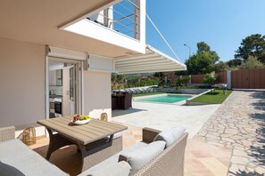 A patio with outdoor furniture, a swimming pool, and a view of the surrounding landscape.