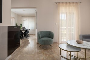 Una sala de estar moderna con una mesa redonda, un sillón verde y un sofá.
