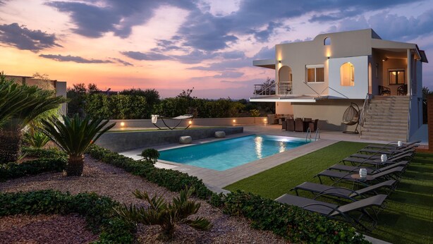 Et moderne hus med swimmingpool, udendørs møbler og en velplejet have.