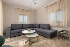 A modern living room with a grey sectional sofa, a round marble coffee table, and two small side tables.