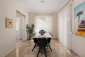Un'area pranzo con tavolo, sedie, una pianta in vaso e un quadro appeso al muro.