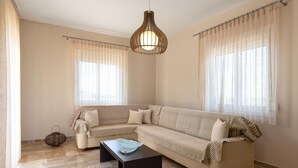 En stue med en hjørnesofa, sofabord og en hængende lampe.