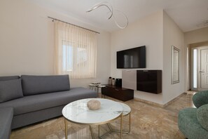 Un soggiorno moderno con un divano grigio, un tavolino da caffè in marmo bianco, una TV a schermo piatto montata a parete e una poltrona verde.