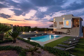 A modern house with a swimming pool, outdoor seating, and a well-maintained garden.