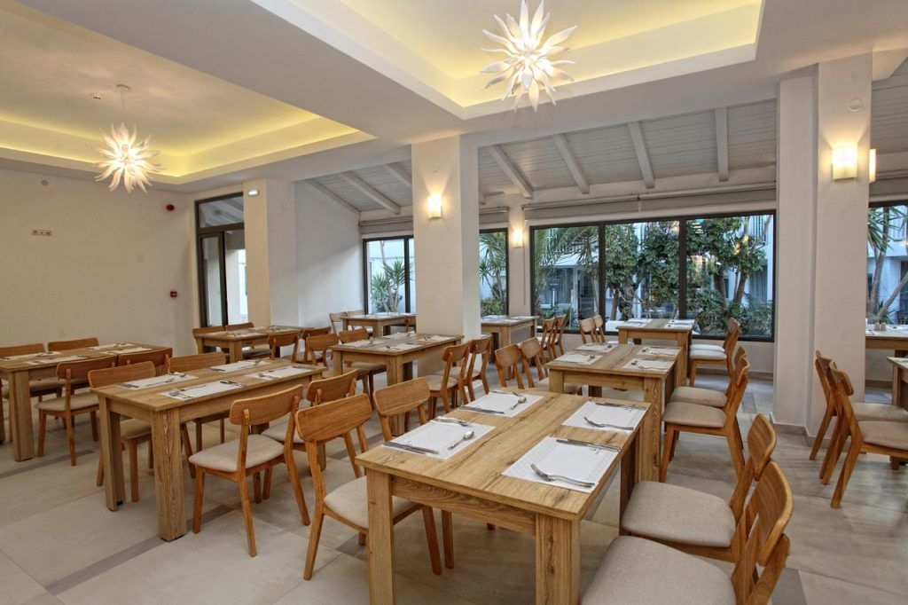 A spacious dining area with wooden tables and chairs, large windows, and modern lighting fixtures.