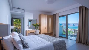 Une chambre d’hôtel avec un grand lit, un bureau avec une chaise, une armoire et un balcon donnant sur la mer.
