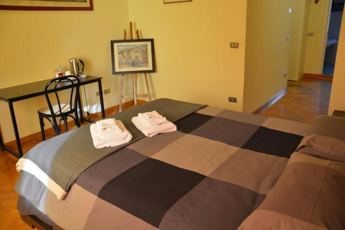 Una habitación de hotel con una cama, un escritorio y una silla. Hay toallas sobre la cama.