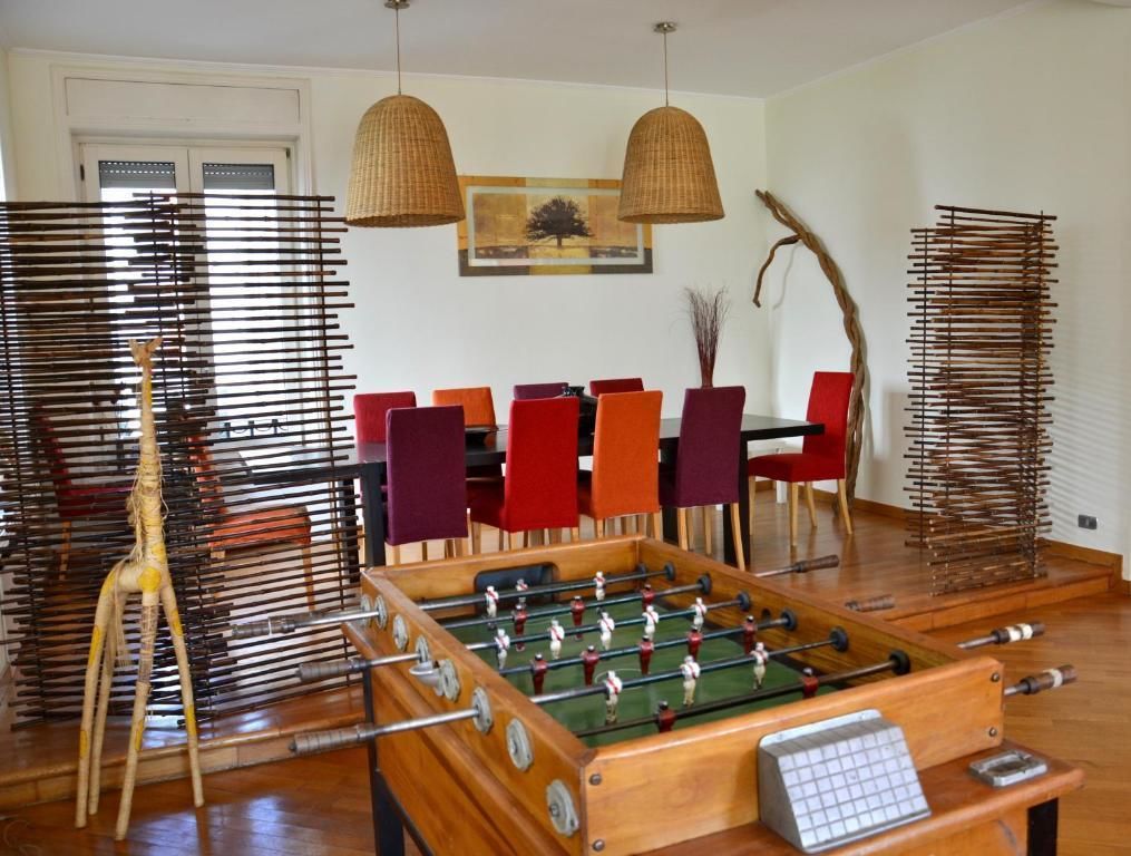 A room with a foosball table, a wooden chair, and a dining table with red and purple chairs.