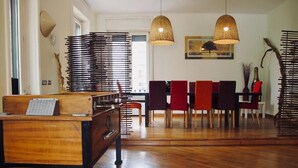 Una habitación amplia con un escritorio de madera, una silla y una zona de comedor con mesa y sillas.