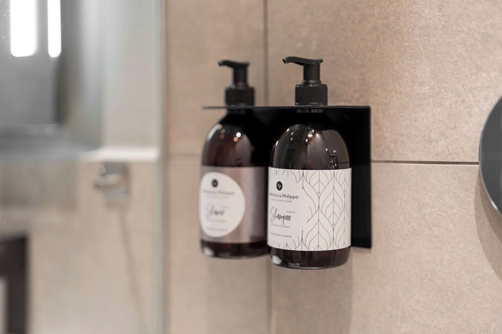 Deux bouteilles de shampoing sur une étagère noire dans une salle de bain.