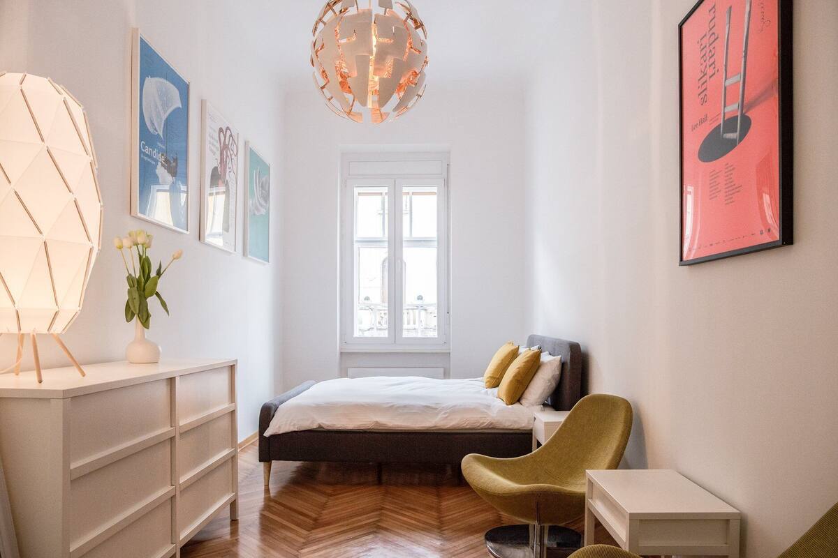 A bedroom with a bed, a chair, a desk, and a window.