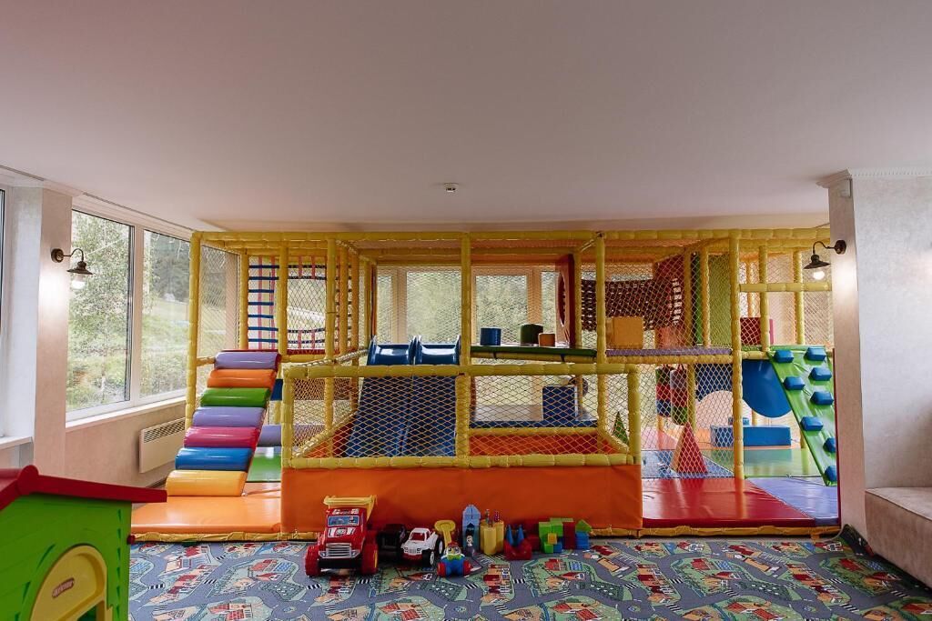A play area with a slide, climbing net, and various play structures.