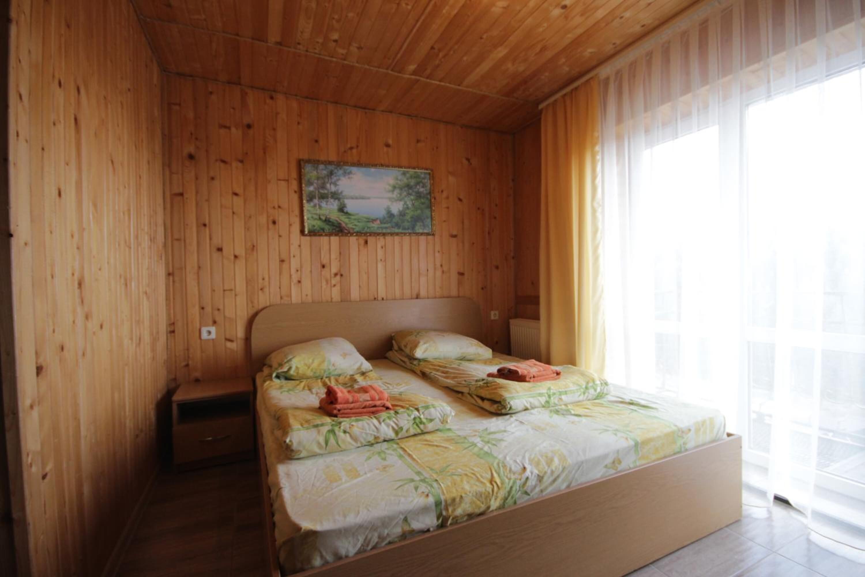 Una habitación con paneles de madera, una cama, una mesita de noche y un cuadro en la pared.