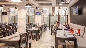 Ein Restaurant mit mehreren Tischen und Stühlen, einer Ziegelwand und großen Fenstern mit Vorhängen.
