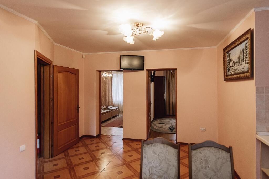 A hallway with a wooden door, a television mounted on the wall, and a framed picture.