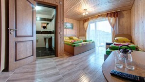 Ein Zimmer mit Holzwänden, einem Bett und einem kleinen Tisch mit Gläsern. Im Hintergrund ist ein Badezimmer durch eine offene Tür erkennbar.