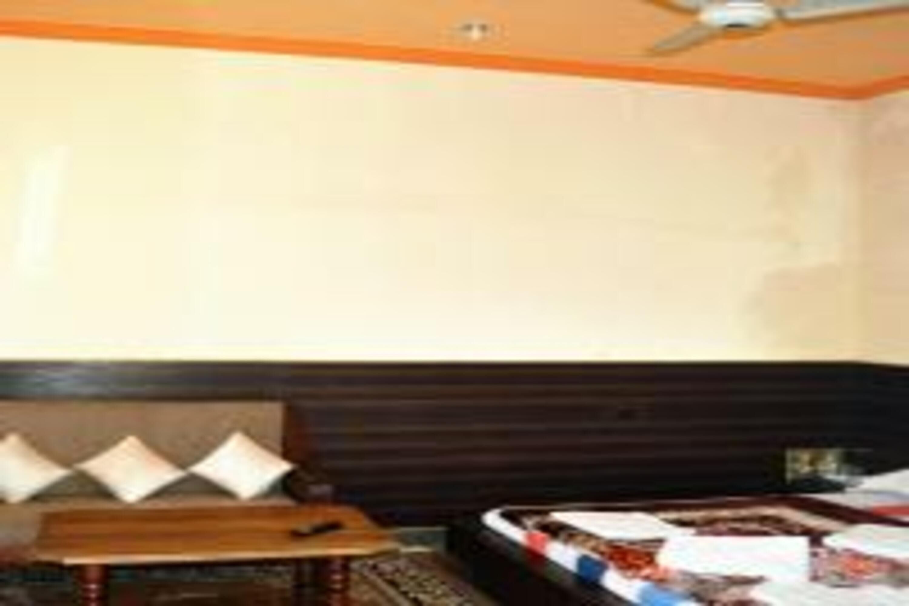 A hotel room with a bed, a wooden table, and a ceiling fan.