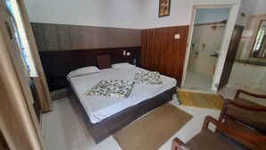 A bedroom with a bed, a wooden headboard, a chair, and a small rug.