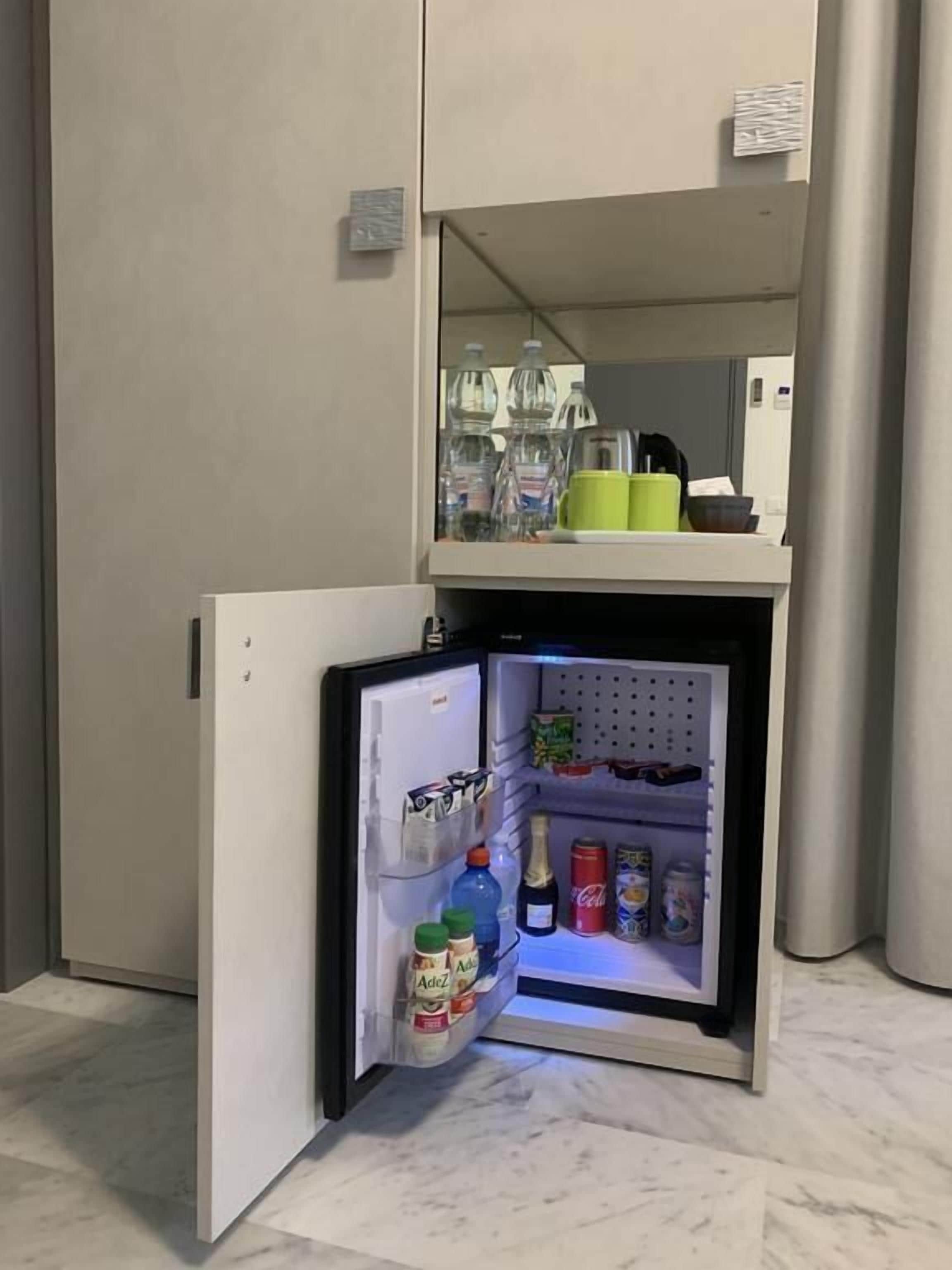 A compact refrigerator with a freezer compartment on top, containing various food items and beverages.