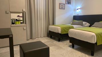 Ein Hotelzimmer mit zwei Betten, einem kleinen Tisch, einer Bank und einem Spiegel.