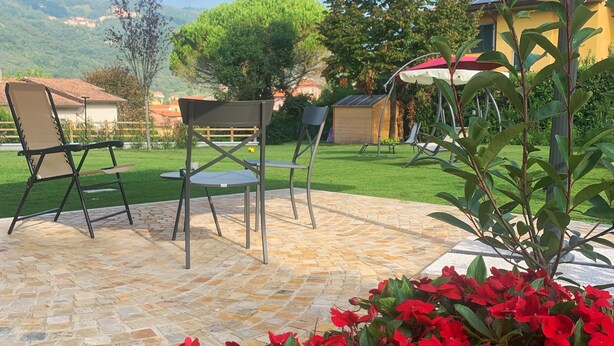 An outdoor patio area with a stone floor, two chairs, a table, and a large umbrella. - B&B Mikeme (Carrara)