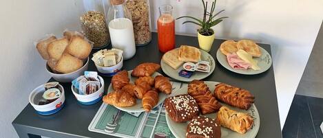 A breakfast buffet with various pastries, bread, and condiments on a table.