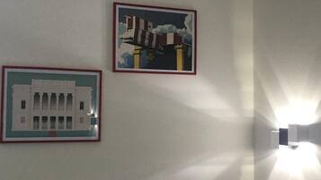 Twee ingekaderde foto's aan een muur, één toont een gebouw met kolommen en de ander een constructie met schoorstenen.