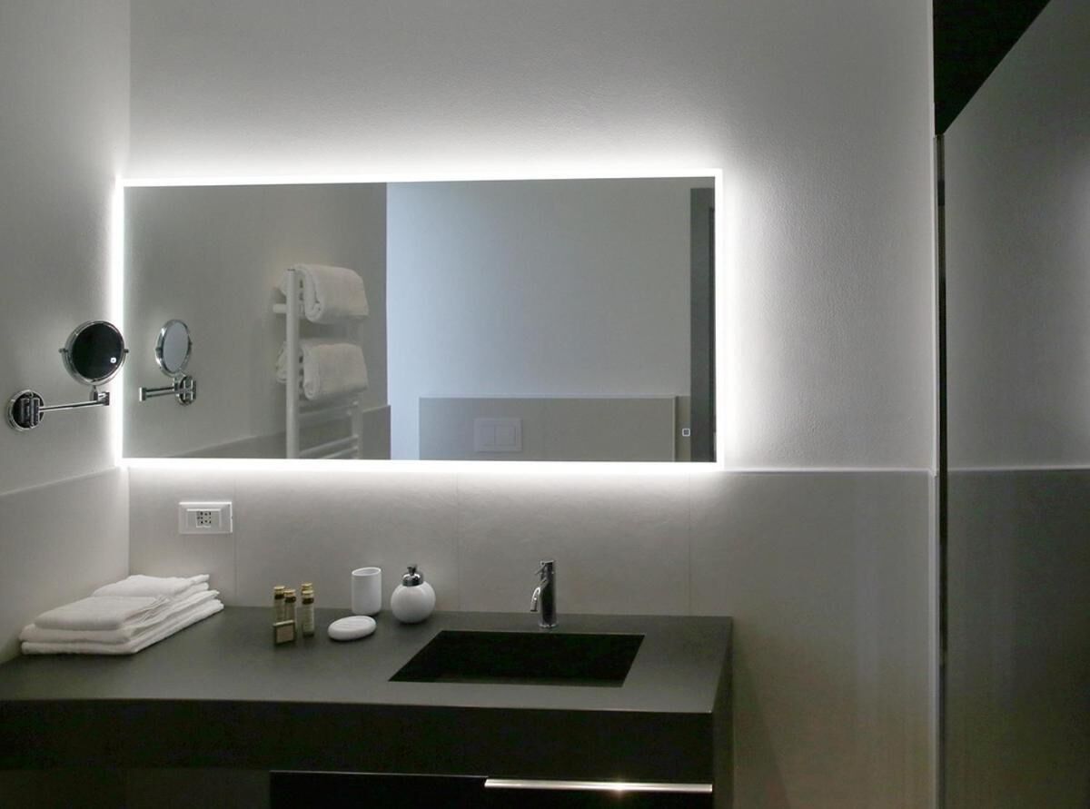 A modern bathroom with a large mirror, a sink, and a towel rack.