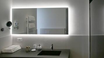 A modern bathroom with a large mirror, a sink, and a towel rack.