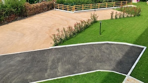 A fenced outdoor area with a sandy surface and a grassy lawn. - B&B Mikeme (Carrara)