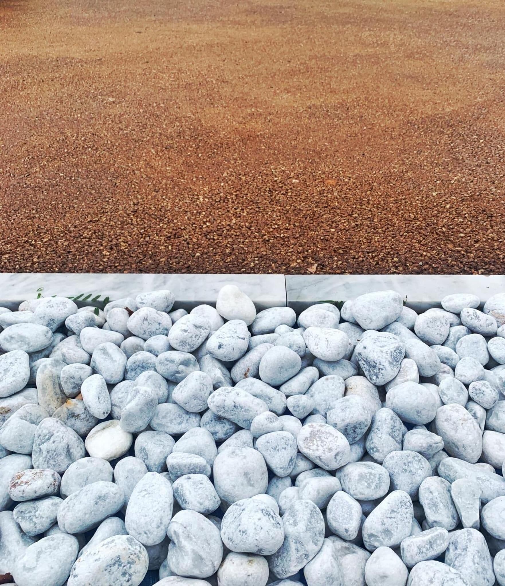 A gravel path leading to a bed of white pebbles.