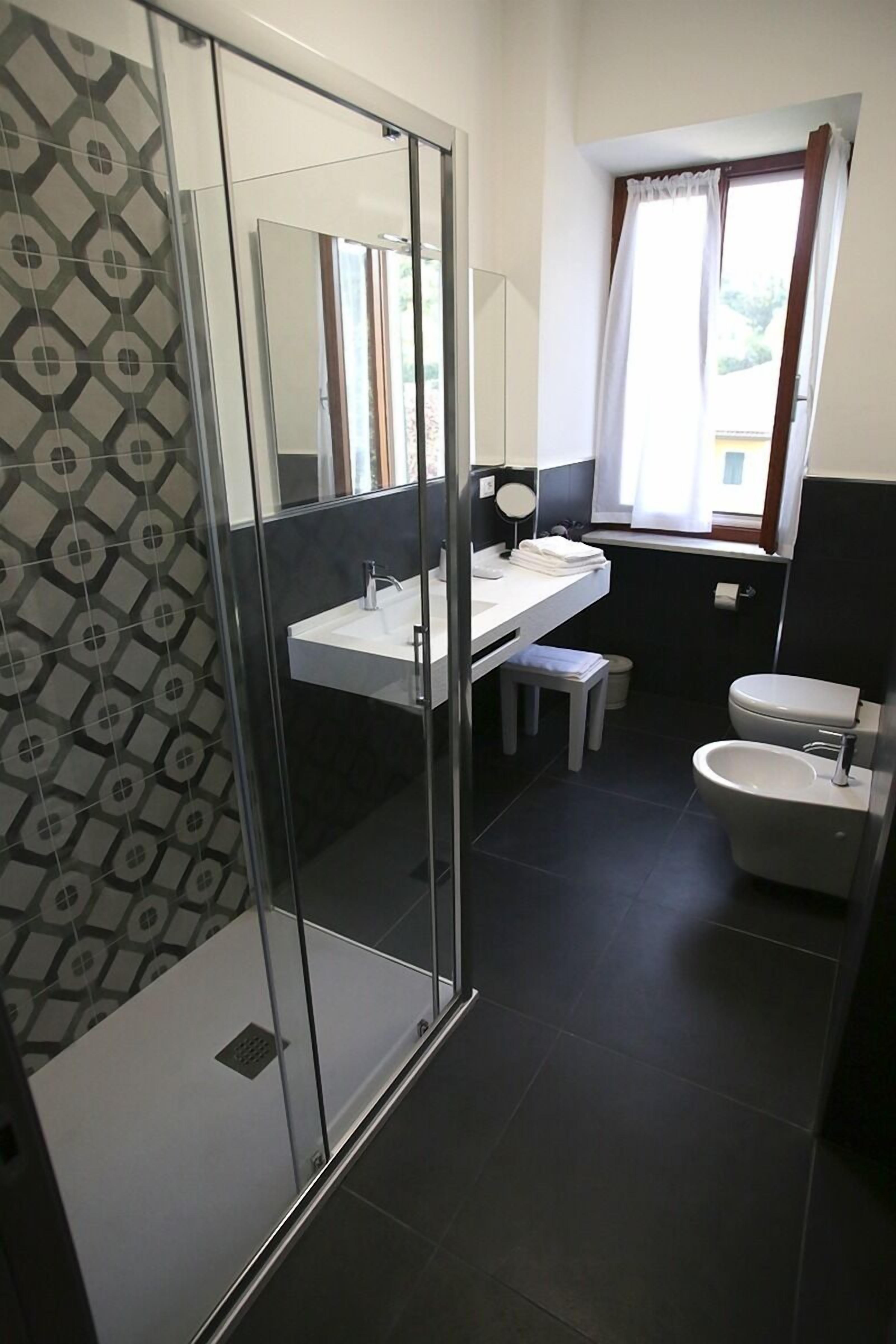 A modern bathroom with a glass shower enclosure, a white sink, and a toilet.