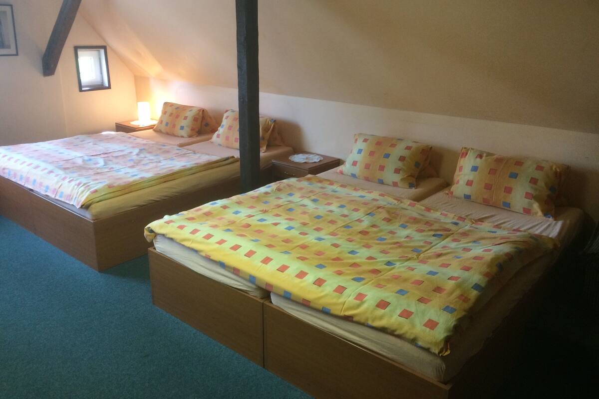 A bedroom with two single beds, each with a pillow and a nightstand.