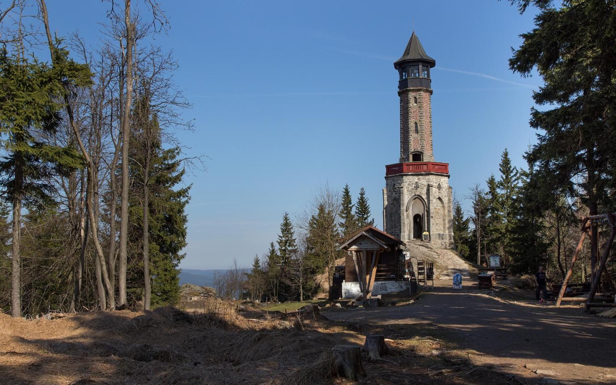 A lighthouse with a stone tower and a wooden structure nearby.