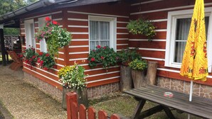 Ein rustikales Gebäude mit Holzverkleidung, Blumenkästen an den Fenstern und einem Picknicktisch mit Sonnenschirm.