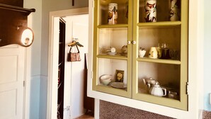 Eine Küche mit einem grünen Schrank, der Geschirr und eine Tür mit einem Kreuz an der Wand enthält.