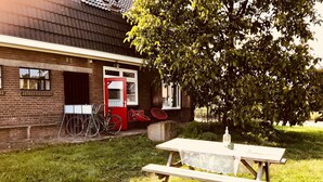 Ein rustikales Gebäude mit roter Tür, einem Fahrrad und einem Picknicktisch im Vordergrund.