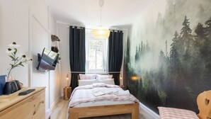 Una camera da letto con un letto, una cassettiera, una TV, un quadro e una finestra.
