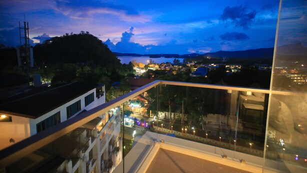 A view from a balcony overlooking a town at dusk with buildings and a hill in the distance.