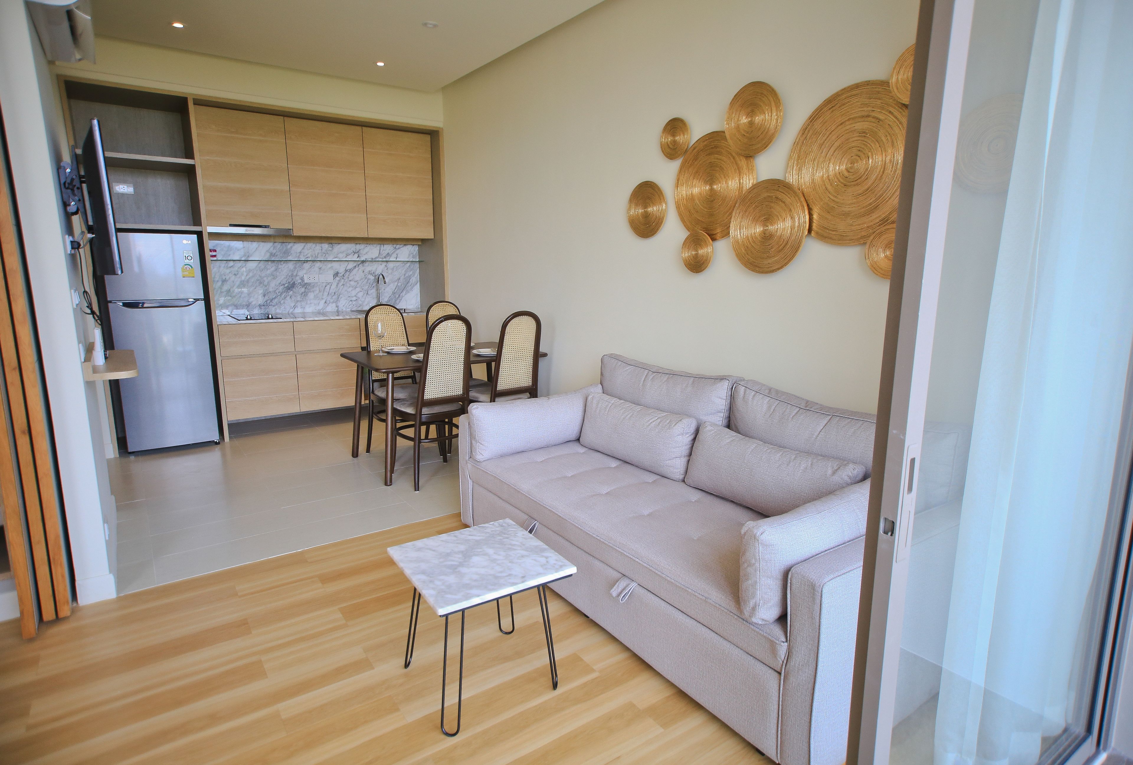 Una sala moderna con un sofá, una mesita y un comedor con sillas.