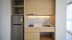 A compact kitchen with a built-in refrigerator, a sink, and wooden cabinets.