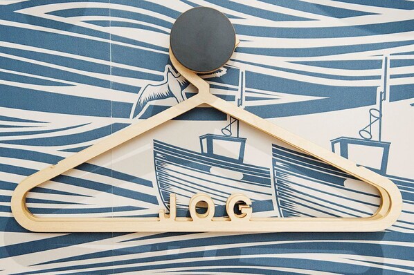 Una percha de madera con temática náutica, que incluye un diseño de barco y ancla, y la palabra "LOG" en ella.