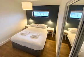 Une chambre d’hôtel avec un lit, des tables de chevet, une télévision et un miroir.