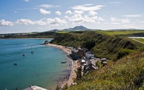Une zone côtière avec une plage, des bateaux et une montagne en arrière-plan.