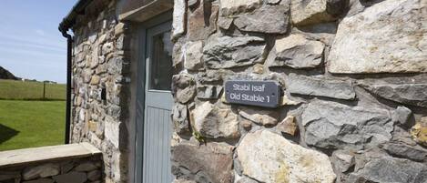 A stone building with a sign reading "Stabl Isaf Old Stable".