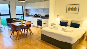 A modern hotel room with a bed, bedside tables, a dining area with a table and chairs, a kitchenette, and a large window with a view. - A john o'groat that sleeps 2 guests  in 1 bedroom (Wick)