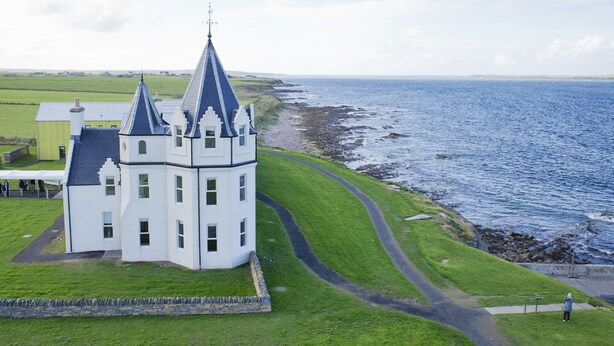 A white building with a tower and a lighthouse, located near a rocky coastline. - A john o'groat that sleeps 2 guests  in 1 bedroom (Wick)