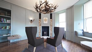 A room with a fireplace, two armchairs, a bookshelf, and a window. - A john o'groat that sleeps 2 guests  in 1 bedroom (Wick)