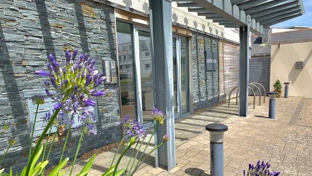 A modern building with a stone facade, a covered outdoor area, and a sign reading "LIGHTHOUSE". - A fistral beach that sleeps 4 guests  in 2 bedrooms (Newquay)