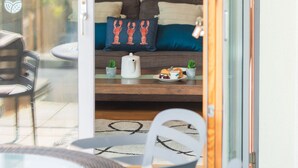 A cozy living area with a sofa, pillows, a small table with a teapot, and a plate of food. - A fistral beach that sleeps 4 guests  in 2 bedrooms (Newquay)
